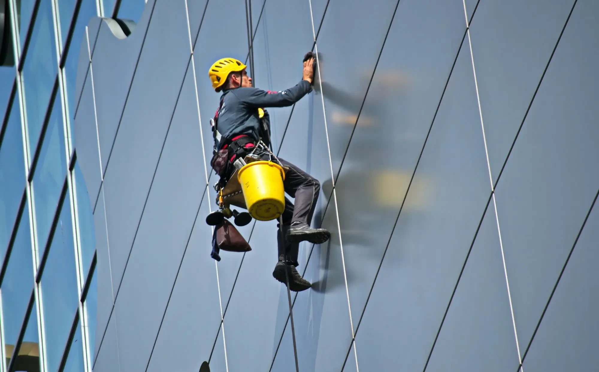 Rope access technician cleaning a glass facade on a high rise building in Perth